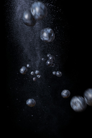 Flying handful of blueberries on a black background. Dynamic photo of berries. Vertical orientationの写真素材