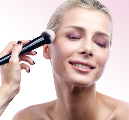 Close-up of the work of a professional makeup artist. To powder the face. Beauty portrait of beautiful young woman with perfect skin and make-upの写真素材