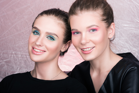 Portrait of two young pretty women. Bright professional makeup. Pink backgroundの写真素材