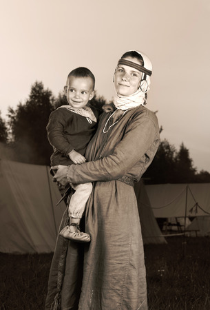 Tinted antique portrait of a slavic woman with a child in costume history. Mother and son. The image of a man from the past. Vintage clothing. Photography outdoorsの写真素材
