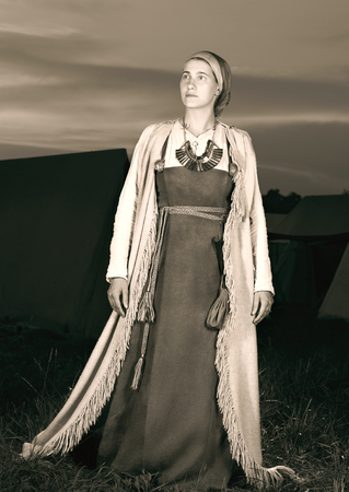 Toned portrait in full length of a young woman in historical costume. The image of a man from the past. Vintage clothing. The sunset in the backgroundの写真素材