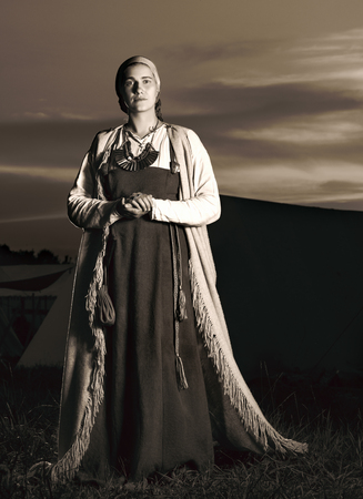 Toned vertical portrait in full length of a young woman in historical costume. The image of a man from the past. Vintage clothing. The sunset in the backgroundの写真素材