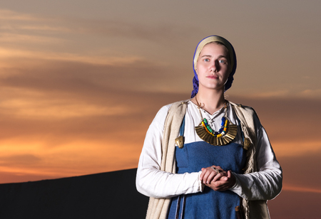 Horizontal portrait in full length of a young woman in historical costume. The image of a man from the past. Vintage clothing. The sunset in the backgroundの写真素材