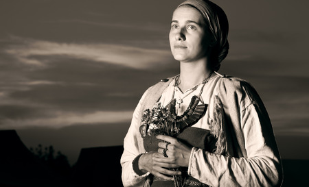 Tinted antique closeup portrait of slavic woman from the past. Historical reconstruction of the image. A photo of the evening outdoors. The sunset in the backgroundの写真素材