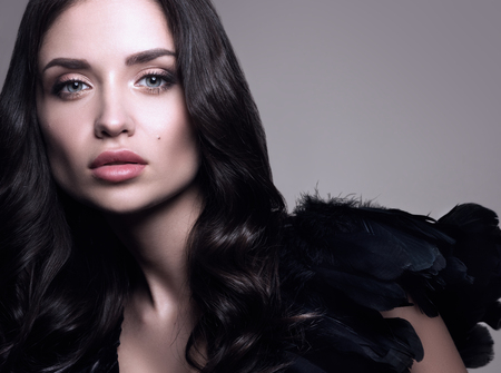 Horizontal beauty portrait of a beautiful young woman in black. Professional makeup and hairstyle. A neutral backgroundの写真素材