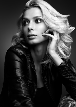 Black and white sensual portrait of a beautiful young woman. Blonde in a leather jacket on a dark backgroundの写真素材