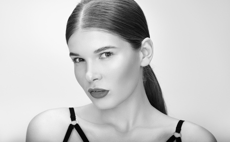 Black and white beauty portrait of beautiful young woman with collected hair. Professional bright make-up. A neutral grey backgroundの写真素材