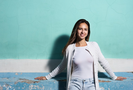 The style and fashion. Young woman in white clothes standing at the bright walls. The free space in the imageの写真素材