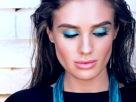 Beauty closeup portrait of beautiful young woman looking down. Professional makeup and wet hair. Turquoise necklace on her neckの写真素材
