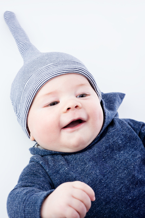 Cute baby in a hat. Closeup happy young boy. Neutral light backgroundの写真素材