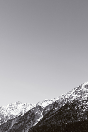 Black-and-white Alpine background. High mountains with snow. Free space