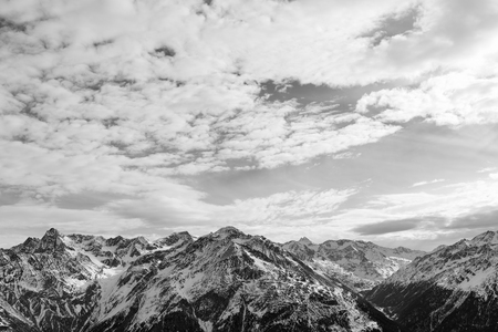 Black-and-white Alpine landscape. The tops of the mountains in the snow and cloudy skyの写真素材