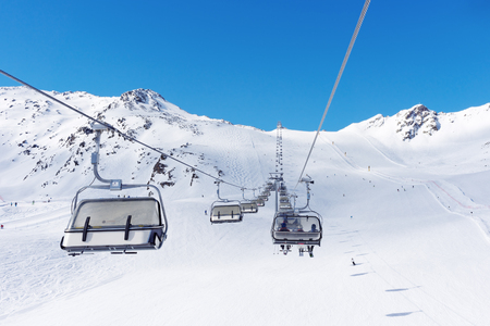Cable car at a ski resort. Skiers ascend the mountain in the chair lift. A Sunny weekend in the Alpsの写真素材
