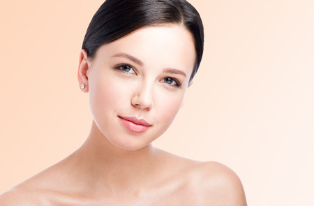 Closeup beauty portrait of beautiful young woman. Perfect clean skin and gentle look. Light backgroundの写真素材