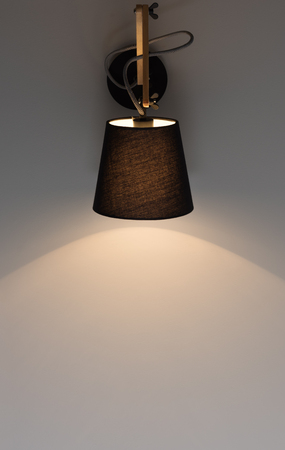 Black modern wall light shines on a dark gray wall. Free spaceの写真素材