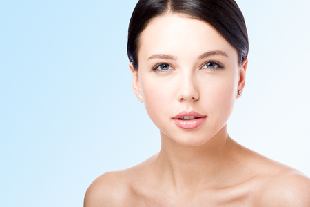 Ð¡loseup beauty portrait. The face of a beautiful young woman. Lips. Perfect skin. Isolated on blue backgroundの写真素材