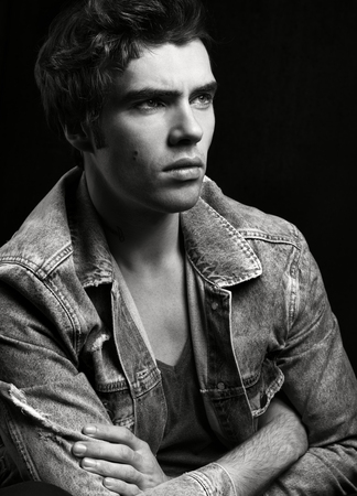 Black and white portrait of young handsome man on black background. A serious lookの写真素材