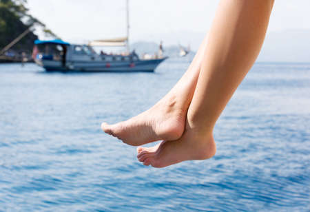 Female feet amid ship at sea. Rest on a yacht. A young woman sunbathes on the sunの写真素材