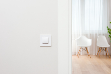 Wall switch in light interior. Modern, beautiful, clean apartment in the background