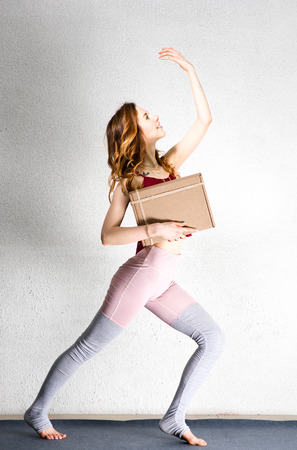 Beautiful young woman posing with a box in her hands. Package for yoga classes. Sports trainingの写真素材