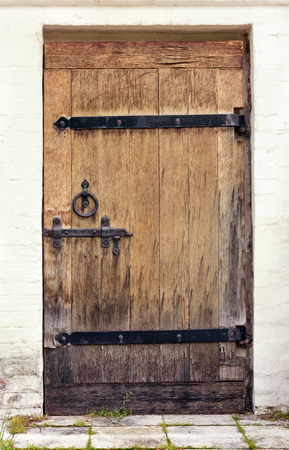 Old wooden door with a deadbolt and forged loopsの写真素材