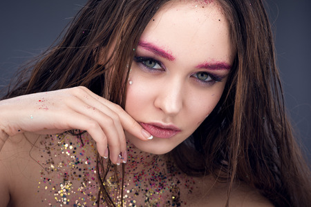 Close up fashion portrait of young sexy woman with bright make-up and sequins at the neck. Sensual look. The dark backgroundの写真素材