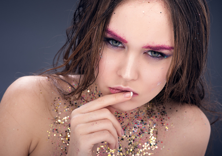 Closeup portrait of young sexy woman with bright make-up and sequins at the neck. Sensual look. The dark backgroundの写真素材