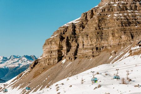 Cable car in the ski resort. Massive rock and mountains on the horizon. Winter holidays in the Alpsの写真素材