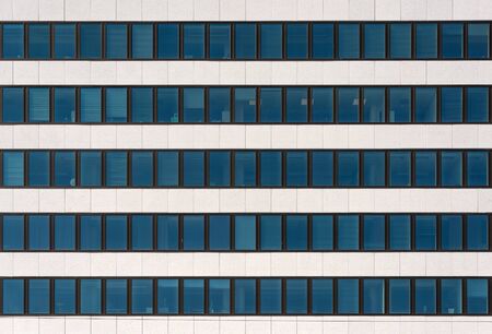 A fragment of the facade of a modern office building. Windows and light decorative stone....