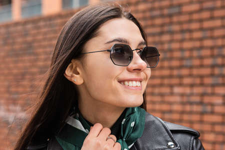 Portrait of a cheerful young woman close-up in the open air. Sunglasses and leather jacketの写真素材