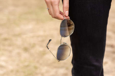 Sunglasses in the woman's hand. Outdoor close-upの写真素材
