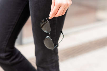 A stylish accessory. Close-up of sunglasses in a woman's hand.の写真素材