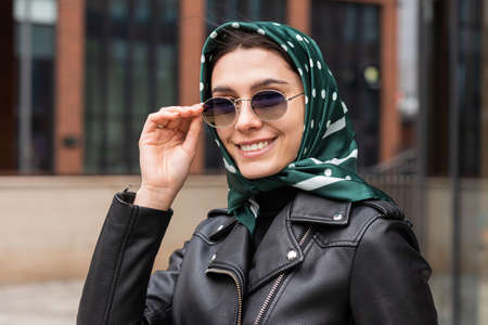 Portrait of a stylish young woman in a headscarf and sunglasses outdoorsの写真素材
