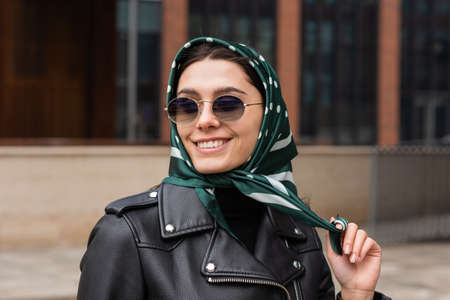 Portrait of a stylish young woman in a headscarf and sunglasses outdoors.の写真素材