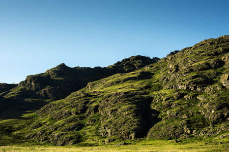 Mountain close-up. Rocky slope with green grassの写真素材