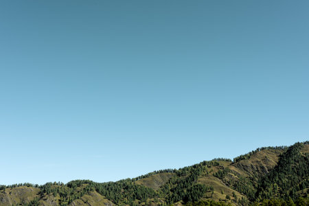 The top of the green hills against the blue sky. Natural background with free spaceの写真素材