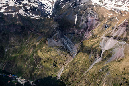 Snow mountains with grass and village in the bottom. Panoramic view from the high spot.の写真素材