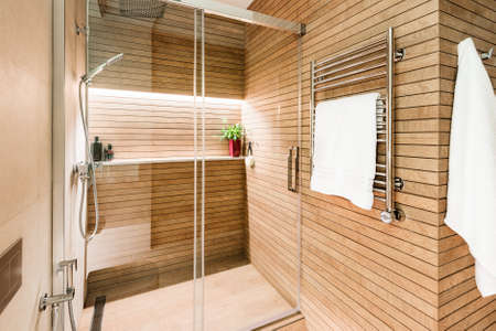 Modern wooden-effect bathroom with glass shower cabin and heated towel rail.の写真素材