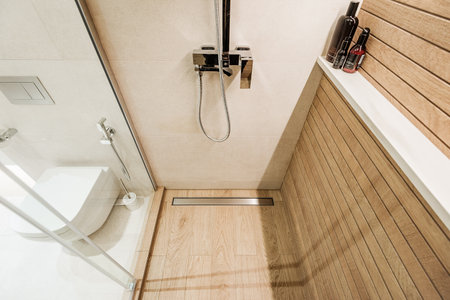 Modern wooden-effect bathroom with glass shower cabin and white toilit.の写真素材