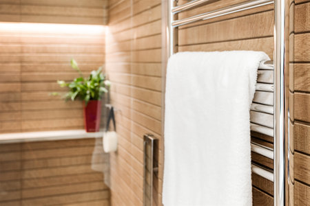 Wooden bathroom interior with heated towel rail and white towel on it.の写真素材