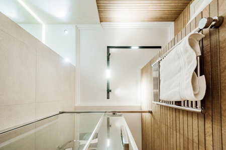 Bottom view of bathroom interior with glass shower cabin and towel rail. White ceiling with line lamp in the middle.の写真素材