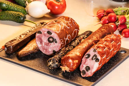 Meat delicacies on the kitchen table, different sausages on a cutting board.の写真素材