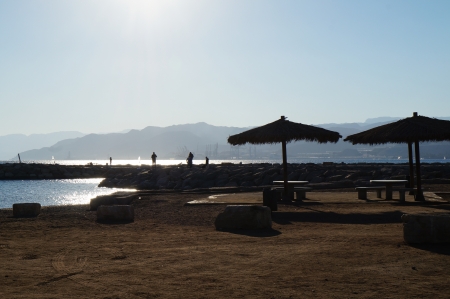 Fishing on the beach in evening time, against sunlight