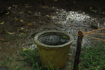 Empty rusted or dust old flower pot filled with rain water in the rainの写真素材
