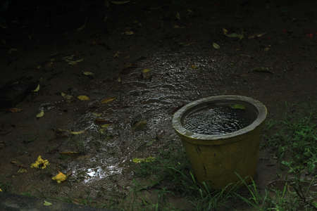 Empty rusted or dust old flower pot filled with rain water in the rainの写真素材