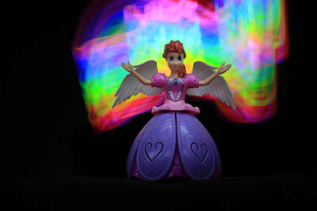 colorful Light painting infront and behind the beautiful angel doll on the black backgroundの写真素材