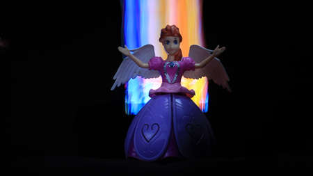 colorful Light painting infront and behind the beautiful angel doll on the black backgroundの写真素材