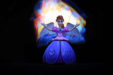 colorful Light painting infront and behind the beautiful angel doll on the black backgroundの写真素材