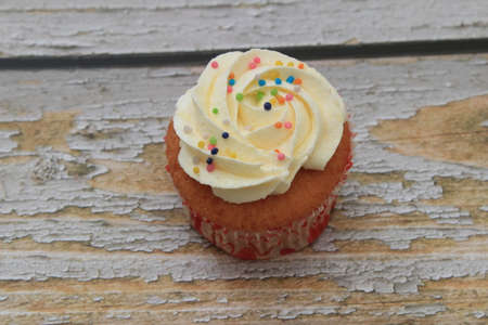 Sweet cake with tutti frutti sprinkles on top on the wooden table white background.の写真素材