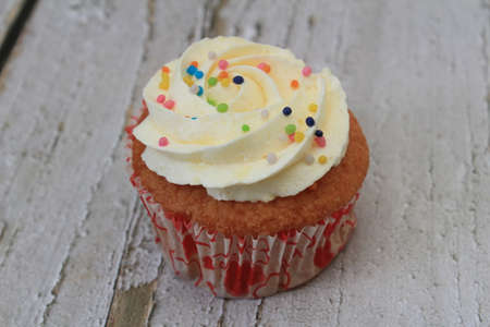 Sweet cake with tutti frutti sprinkles on top on the wooden table white background.の写真素材